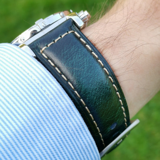 Wrist shot of the Berlin blue full grain leather watch strap. Strap on a males wrist with a shirt sleeve. Grass background.