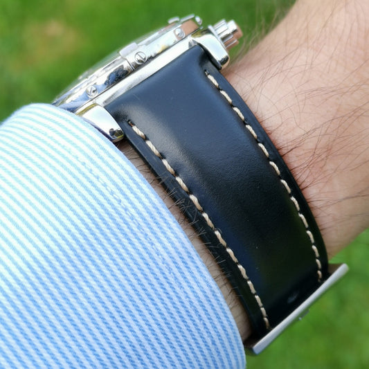 Wrist shot of the Oxford black full grain leather watch strap. Placed on a males wrist with a blue and white sleeve.