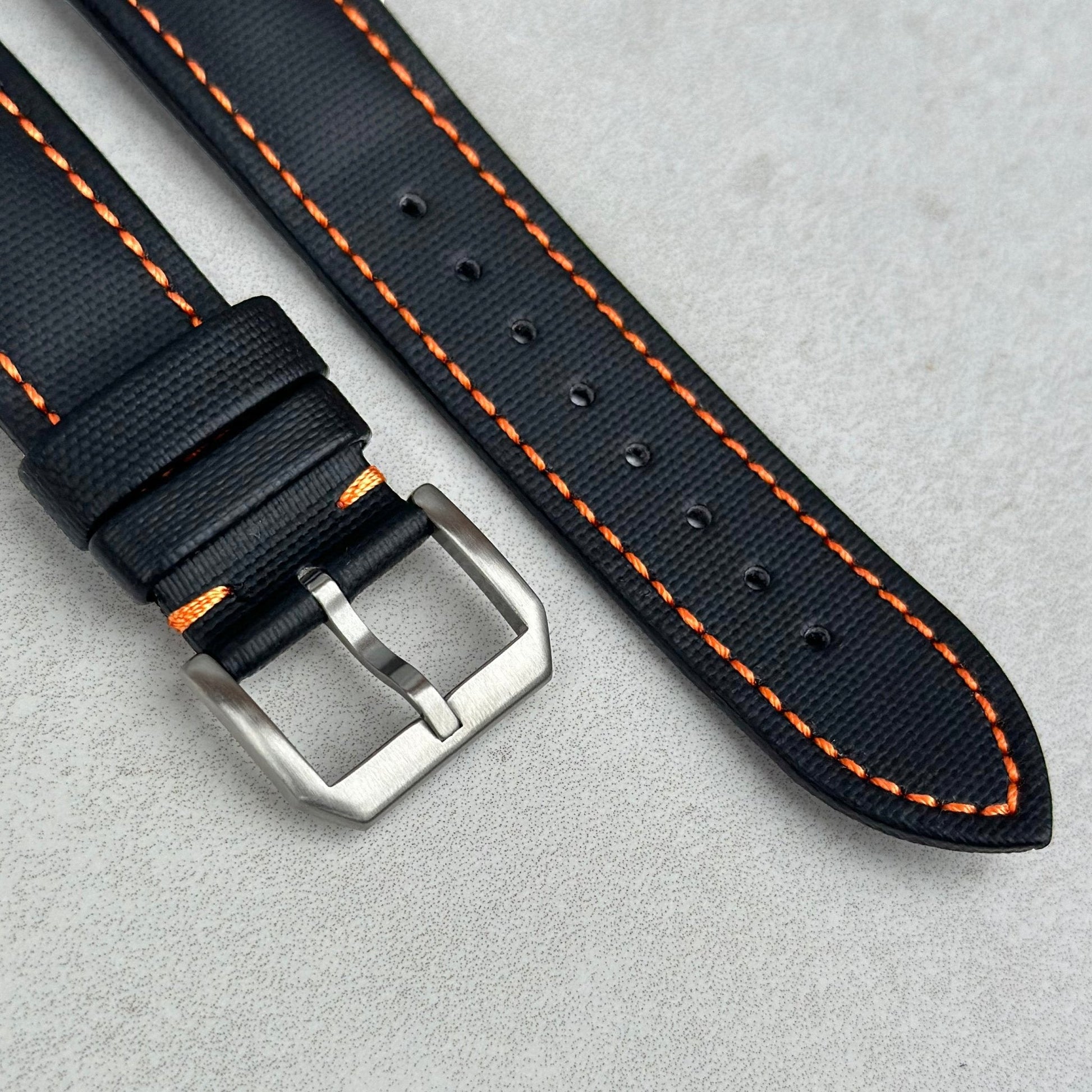 Brushed stainless steel buckle on the Bermuda jet black sail cloth Apple Watch strap with orange stitching.