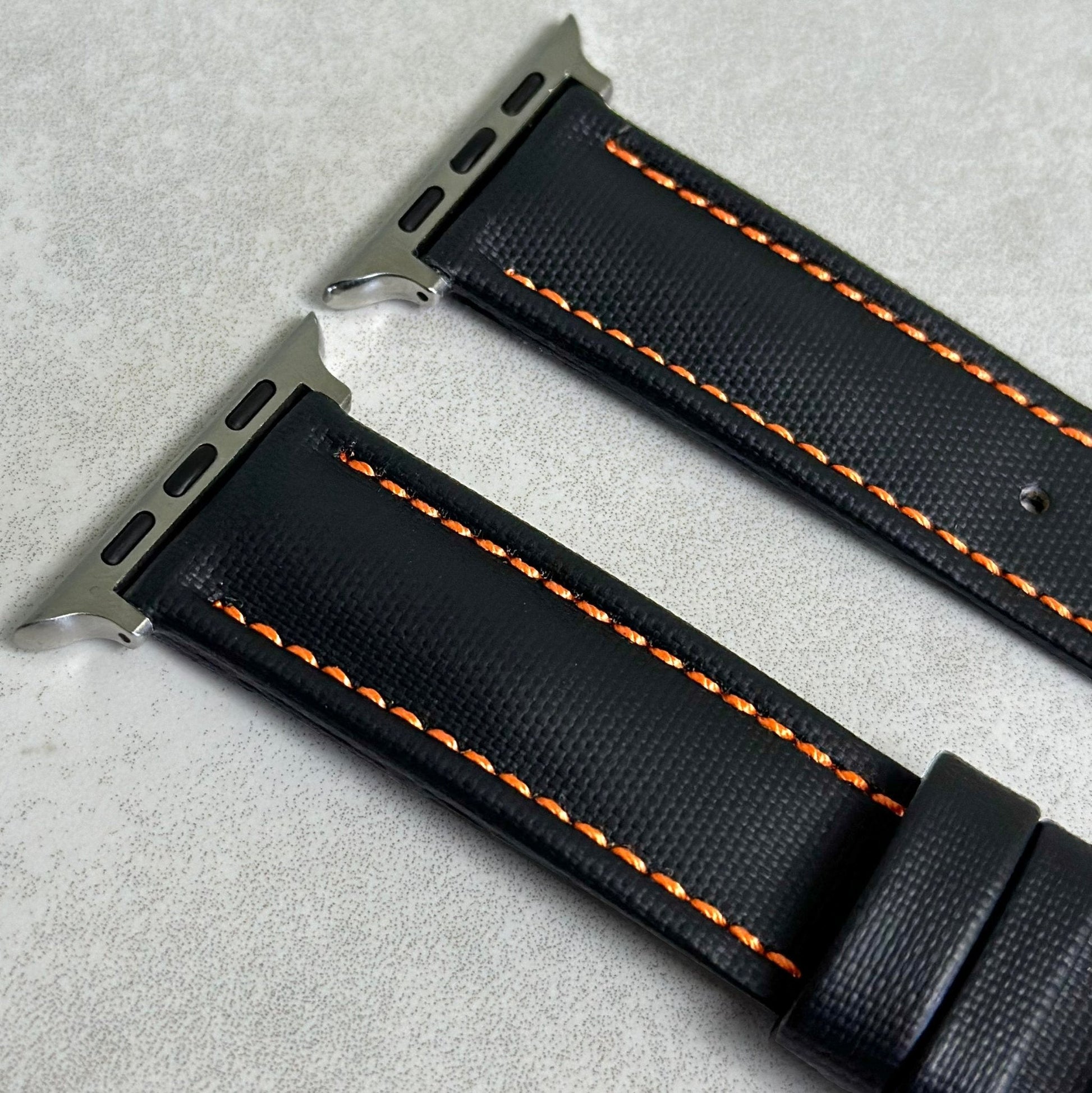 Top of the Bermuda jet black sail cloth Apple Watch strap with contrast orange stitching. Stainless steel connectors.