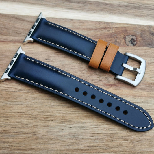 Oxford blue full grain leather apple watch strap placed diagonally on a wood background.